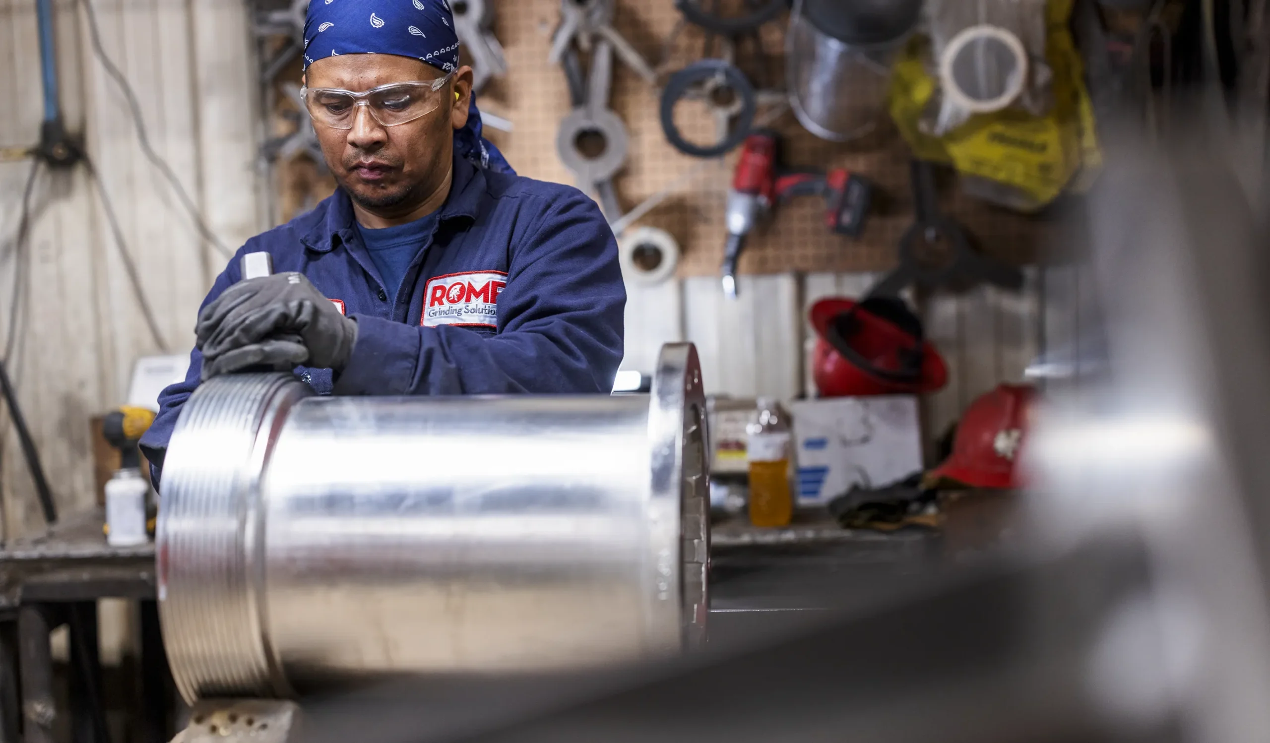 Man in blue working kit Rome logo on pocket working with machine behind on the wall tools attachedl.